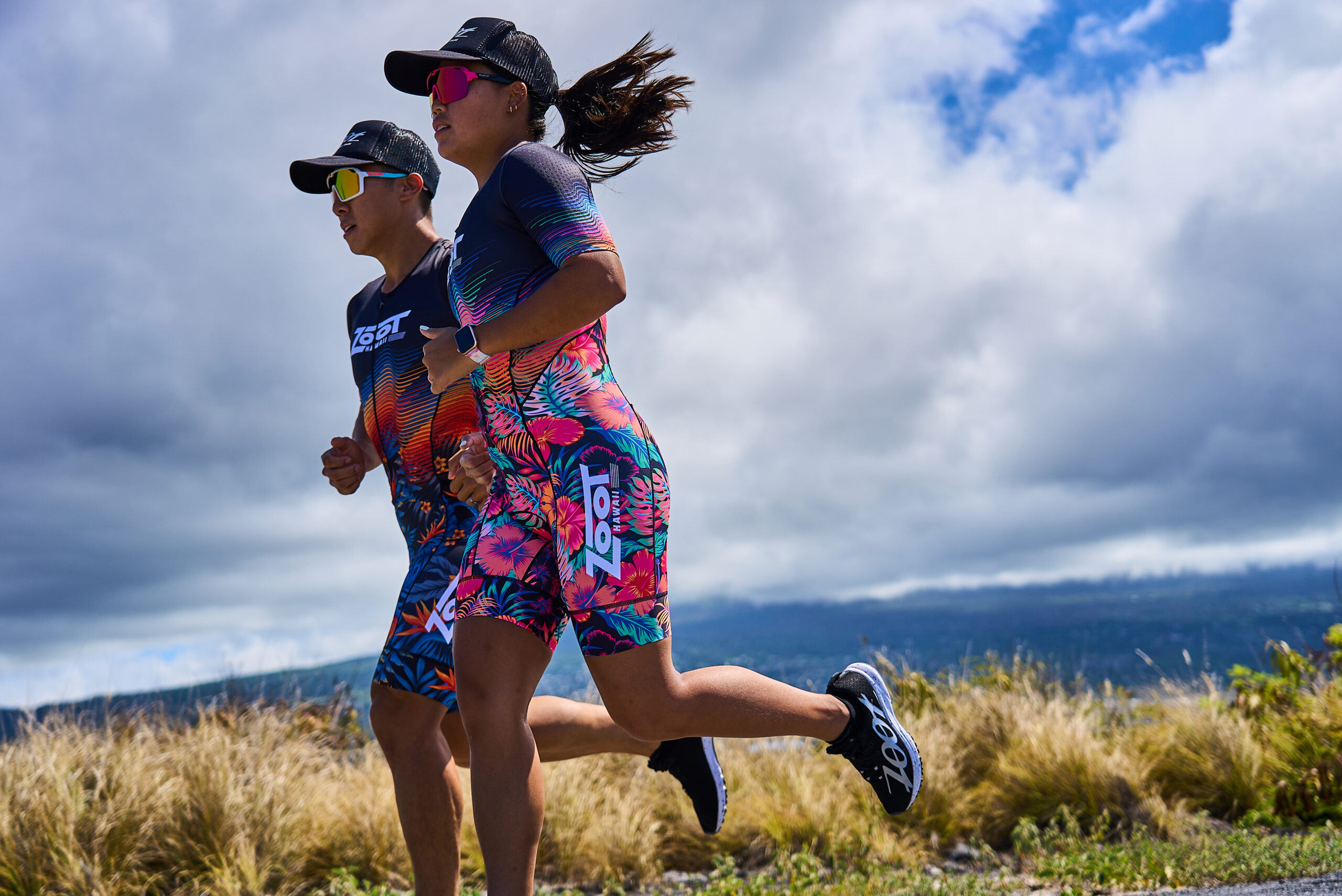 Anthony Chan running alongside his wife in matching Zoot tri kits on a road in Kona, Hawaii